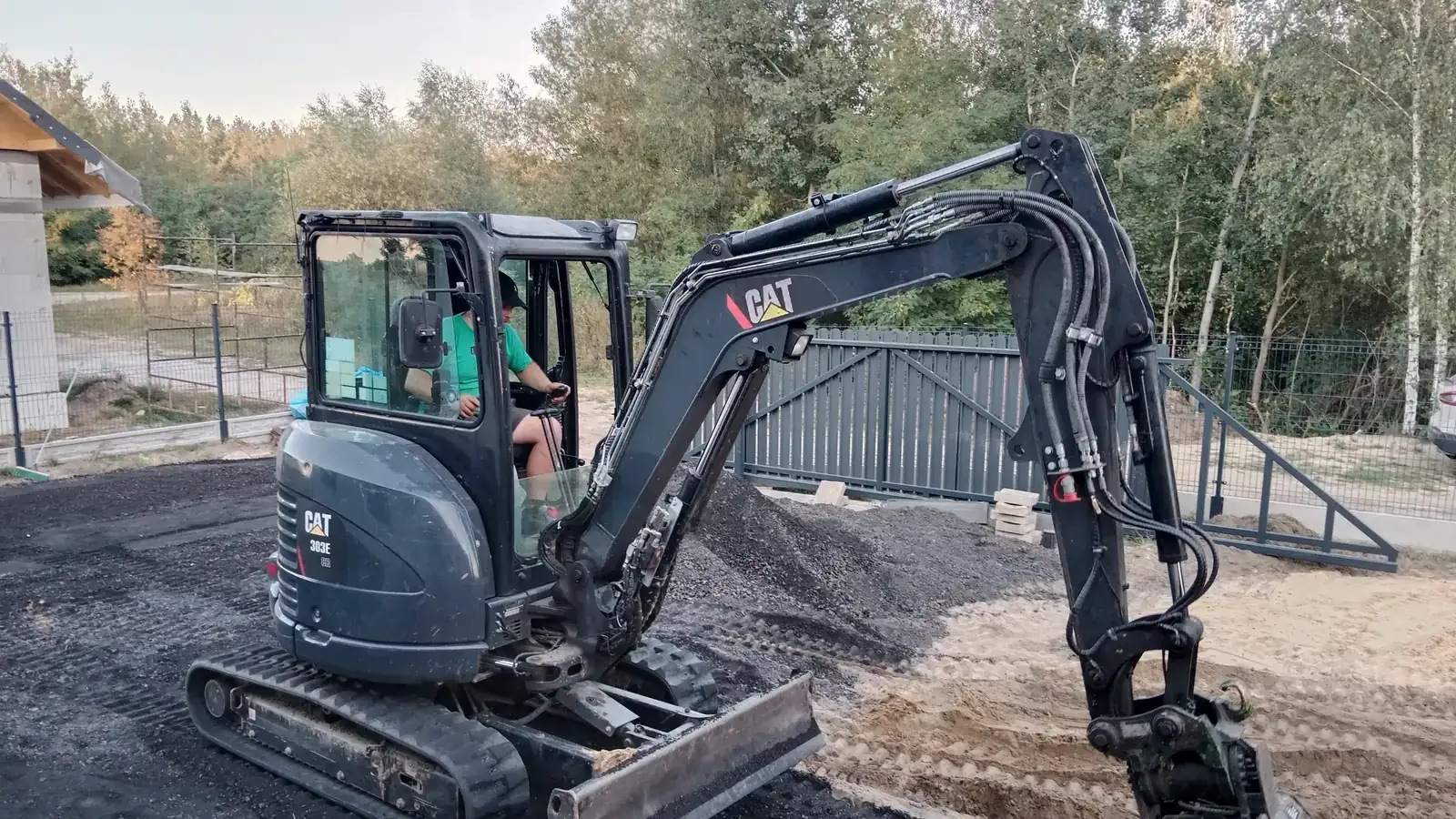 Mini koparka CAT 303E CR rozkłada kruszywo na podjeździe nowego domu w Jedlance