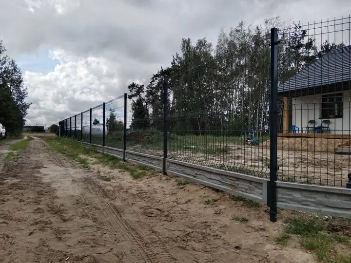Piaszczysta droga dojazdowa wzdłuż ogrodzenia